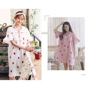 May include: Two women wearing short-sleeved dresses with strawberry patterns. The dress on the left is white with red strawberries, and the dress on the right is pink with red strawberries.