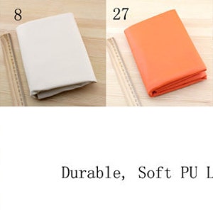 Puede incluir: Cinco muestras de cuero PU suave y duradero en diferentes colores: rosa, blanco, naranja, marr&oacute;n y azul claro. Cada muestra est&aacute; doblada y colocada sobre una superficie de madera con una regla al lado. Los n&uacute;meros 30, 8, 27, 29 y 22B est&aacute;n escritos encima de cada muestra.