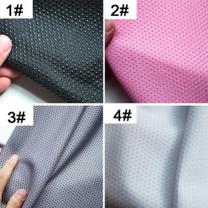 May include: Four samples of fabric with a textured dot pattern. The fabric samples are black, pink, gray, and white.