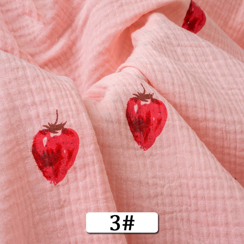 May include: Pink fabric with a white and red strawberry print. The fabric has a textured, gauze-like appearance. The text "3#" is printed on the fabric.