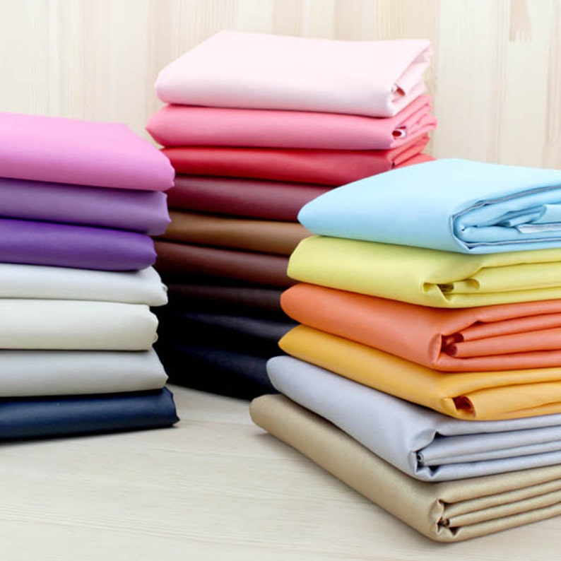 Puede incluir: Un mont&oacute;n de muestras de tela de colores en varios tonos de rosa, morado, azul, amarillo, naranja, marr&oacute;n y beige. Las muestras de tela est&aacute;n dispuestas en un patr&oacute;n escalonado, creando una exhibici&oacute;n visualmente atractiva.