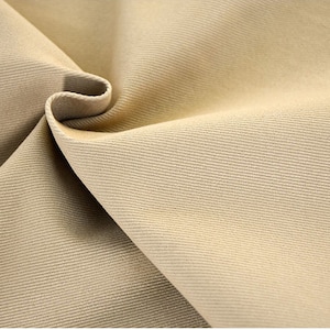 May include: Close-up of a beige fabric with a subtle ribbed texture. The fabric is folded in a way that shows the texture and the way it drapes.