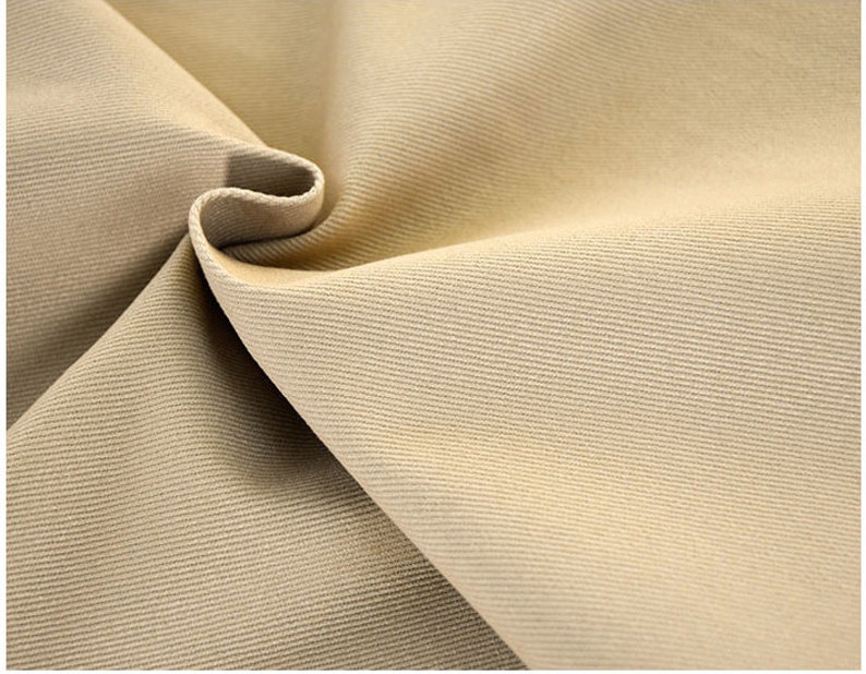 May include: Close-up of a beige fabric with a subtle ribbed texture. The fabric is folded in a way that shows the texture and the way it drapes.