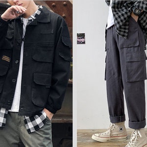 May include: A black utility jacket with a plaid shirt underneath and a pair of grey cargo trousers with multiple pockets.