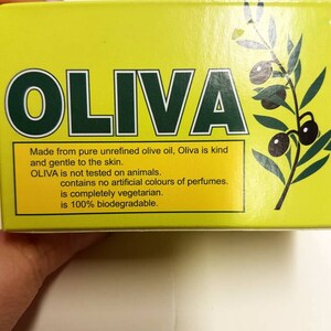 May include: Yellow box with the word "OLIVA" in green letters. The box has a picture of olive branches with olives. The text on the box reads: "Made from pure unrefined olive oil, Oliva is kind and gentle to the skin. OLIVA is not tested on animals. contains no artificial colours of perfumes. is completely vegetarian. is 100% biodegradable."
