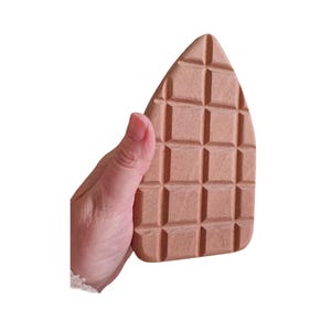 May include: A light brown, rectangular shaped, textured, wooden ironing board with a grid pattern.