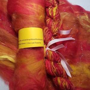 Puede incluir: Un paquete de hilo rojo, naranja y amarillo con una etiqueta amarilla que dice "etsy.com/uk/shop/MarieReddingArts  Christmas Advent 1 One Last Surprise".