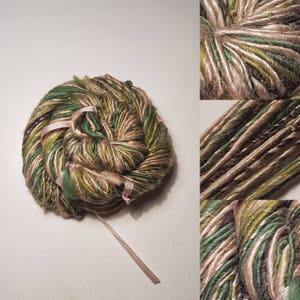 May include: A skein of yarn in shades of green, brown, and beige. The yarn is wound into a ball shape and tied with pink ribbon.