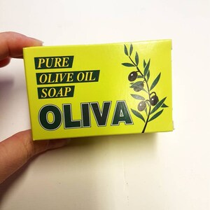 May include: A yellow box with green text and a green olive branch design. The text reads "PURE OLIVE OIL SOAP OLIVA".