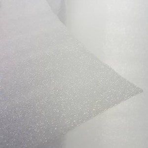 Pode incluir: Close-up de uma folha de espuma branca com uma superf&iacute;cie texturizada. A espuma &eacute; ligeiramente transl&uacute;cida e tem um brilho sutil.