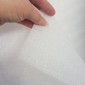 Könnte beinhalten: Weißes Schaumstoffblatt mit einer strukturierten Oberfläche. Der Schaumstoff ist flexibel und hat eine leicht unebene Textur.