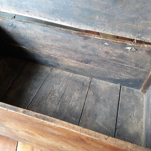 May include: An antique wooden chest with a hinged lid, open to reveal the empty interior. The chest is made of dark wood with a natural finish and has a simple design.