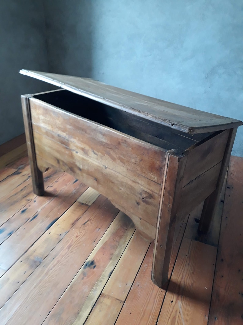 May include: A vintage wooden storage chest with a hinged lid, open to reveal the empty interior. The chest is made of natural wood with a rustic finish and sits on a wooden floor.