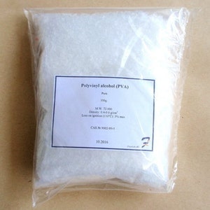 May include: A clear plastic bag filled with white, granular polyvinyl alcohol (PVA). A white label displays the product name, purity, weight (100g), and other specifications. The bag is sealed and sits on a light brown surface.