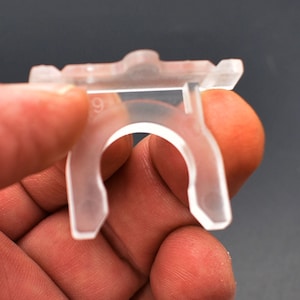 May include: A clear plastic clip with a small hole in the center. The clip has a number "91" printed on it.