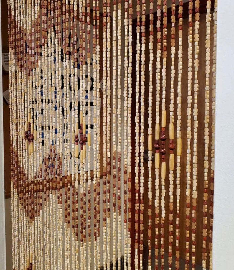 May include: A wooden beaded curtain with alternating light brown and dark brown beads. The curtain is hanging in a doorway.