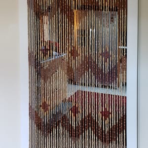 May include: A wooden bead curtain with alternating light brown and dark brown beads hanging in a doorway. The curtain is about 3 feet wide and 7 feet tall. The beads are strung on a wooden rod.