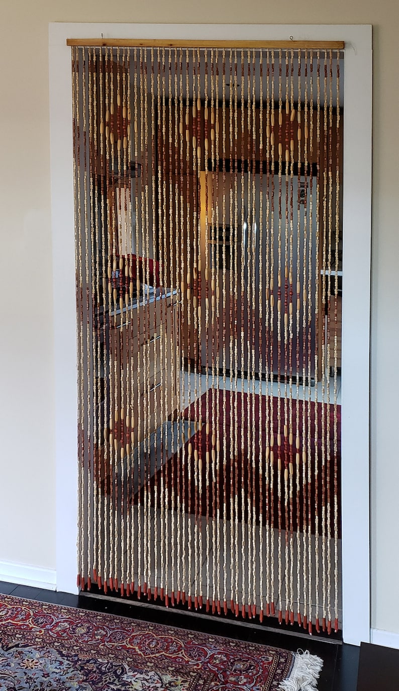 May include: A wooden bead curtain with alternating light brown and dark brown beads hanging in a doorway. The curtain is about 3 feet wide and 7 feet tall. The beads are strung on a wooden rod.
