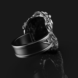 May include: A silver ring with a lion head design. The ring has a black band with a lightning bolt design.