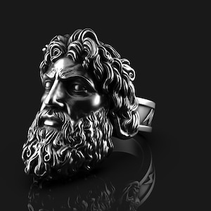 May include: A silver ring with a detailed sculpture of a man's face with a beard. The ring band has a textured design.