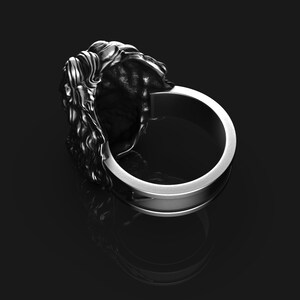 May include: Silver ring with a detailed lion head design. The ring is wide and has a smooth band.