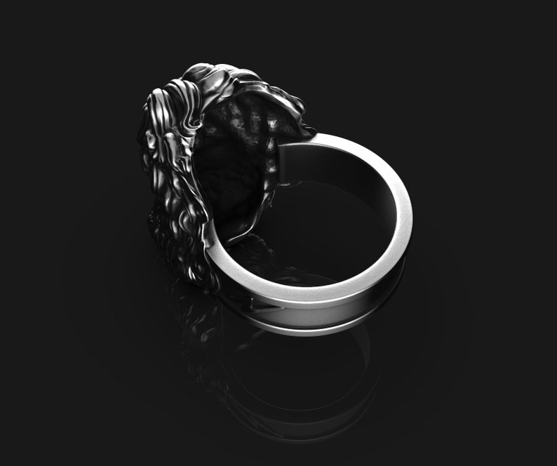 May include: Silver ring with a detailed lion head design. The ring is wide and has a smooth band.