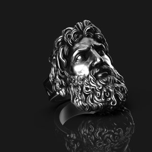 May include: A silver ring with a detailed sculpture of a man's face with a beard. The ring is set against a black background.