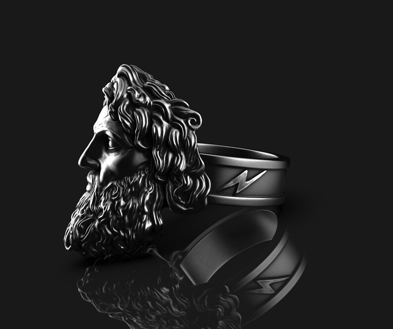 May include: A silver ring with a detailed sculpture of a man's head with a beard and a lightning bolt design on the band.