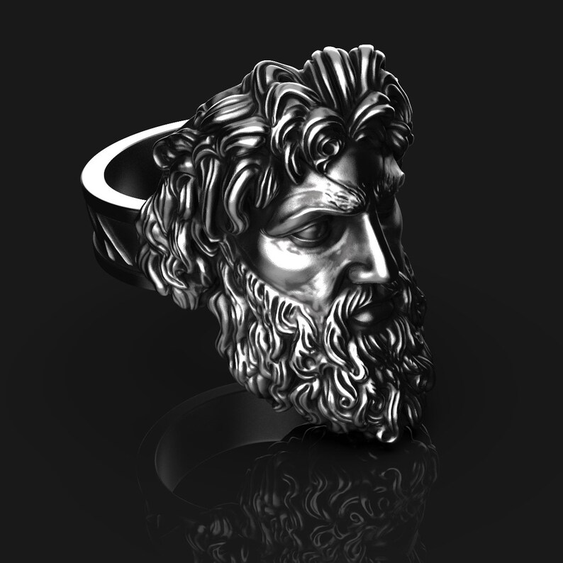 May include: A silver ring with a detailed sculpture of a man's head with a beard and long hair. The ring is made of metal and has a smooth, polished finish.