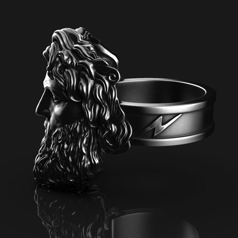 May include: A silver ring with a detailed sculpture of a man's head with a beard and long hair. The ring band has a lightning bolt design.