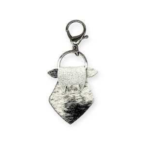 May include: Silver-toned keychain with a small, diamond-shaped bag charm. The bag has a flap with a small, round handle.