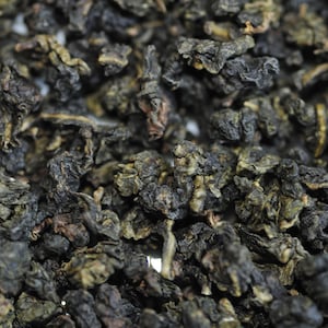 Könnte beinhalten: Nahaufnahme von getrockneten Oolong-Teeblättern, einer Art chinesischem Tee, in dunkelbrauner und grüner Farbe.