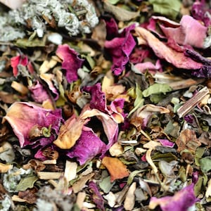 May include: Close-up of a blend of dried herbs and flowers, including green leaves, white pieces, and pink rose petals.