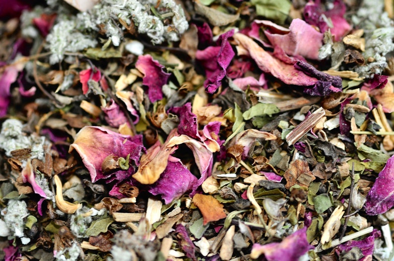 May include: Close-up of a blend of dried herbs and flowers, including green leaves, white pieces, and pink rose petals.