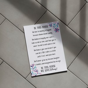 Op de afbeelding: Een printbare wanddecoratie met een bloemenontwerp en de tekst "In dit huis houden we van oneindigheid en verder, want ohana betekent familie. We geloven in happy ends, verhalen die zo oud zijn als de tijd, en dat je nooit te oud bent om een wens te doen. We weten dat als je het kunt dromen, je het kunt doen. Het enige wat je nodig hebt is een beetje geloof, vertrouwen en pixie dust. We zullen nooit opgroeien, want lachen is tijdloos en verbeelding kent geen leeftijd. In dit huis houden we van Disney!"