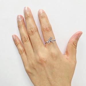 May include: A silver ring with a dragonfly design. The ring is adjustable and can be worn on any finger.