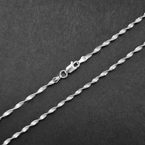 May include: A silver chain necklace with a twisted design. The chain is approximately 18 inches long and has a lobster clasp.
