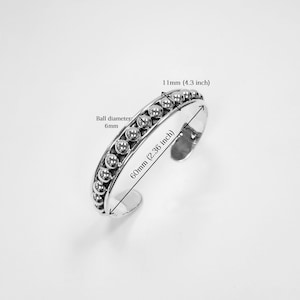 Puede incluir: Pulsera de brazalete de plata con una fila de peque&ntilde;as cuentas. La pulsera mide 60 mm de di&aacute;metro y 110 mm de circunferencia.