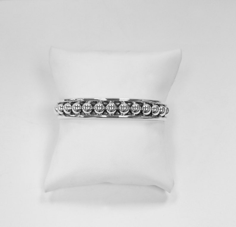Puede incluir: Una pulsera de plata con una fila de cuentas redondas.