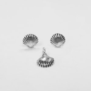 May include: A set of silver seashell earrings and a matching pendant necklace. The seashells are detailed with a textured, ribbed design.