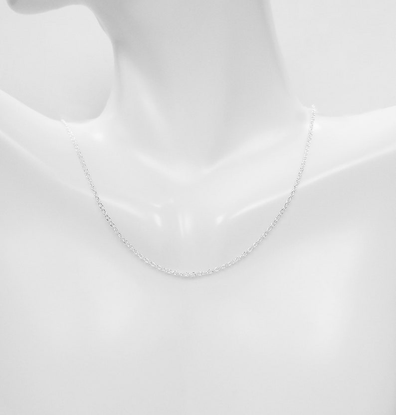 May include: A silver chain necklace on a white mannequin.