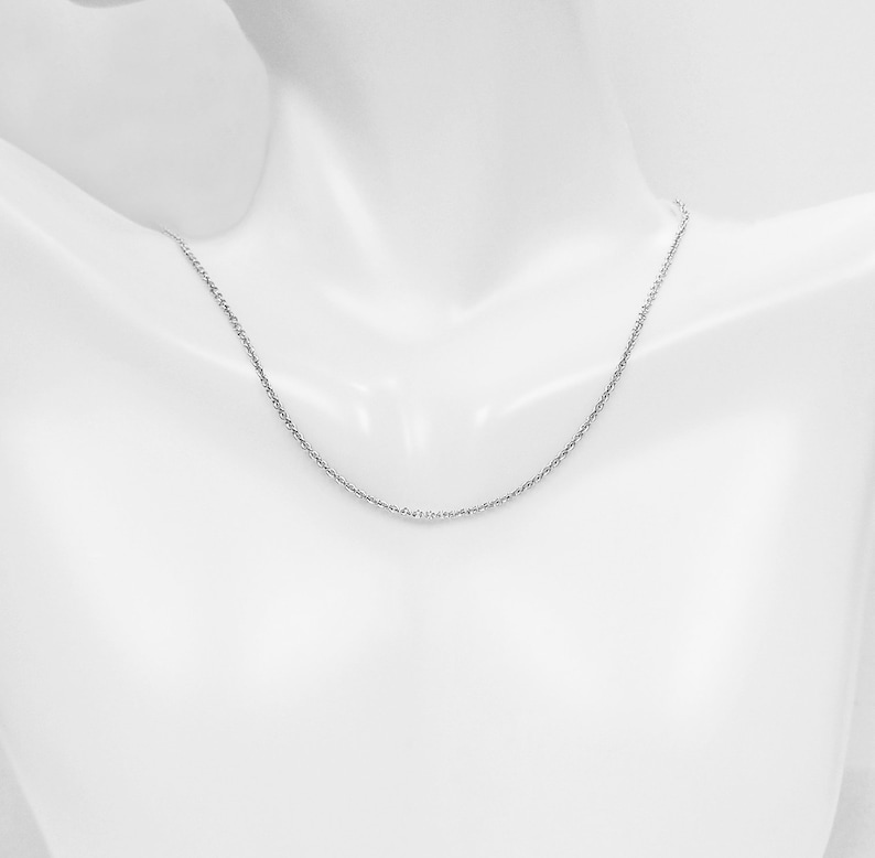 May include: A silver chain necklace on a white mannequin.