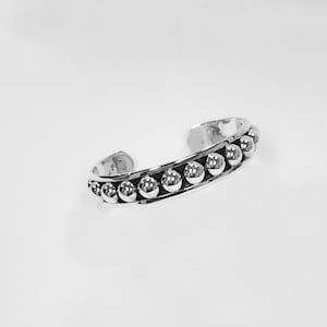 Puede incluir: Una pulsera de plata con una fila de cuentas redondas.