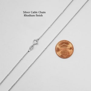 May include: A silver cable chain necklace with a rhodium finish. The chain is shown next to a US penny for size comparison.