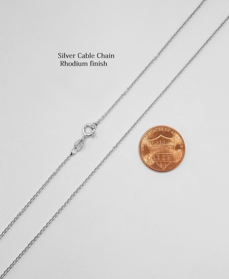 May include: A silver cable chain necklace with a rhodium finish. The chain is shown next to a US penny for size comparison.