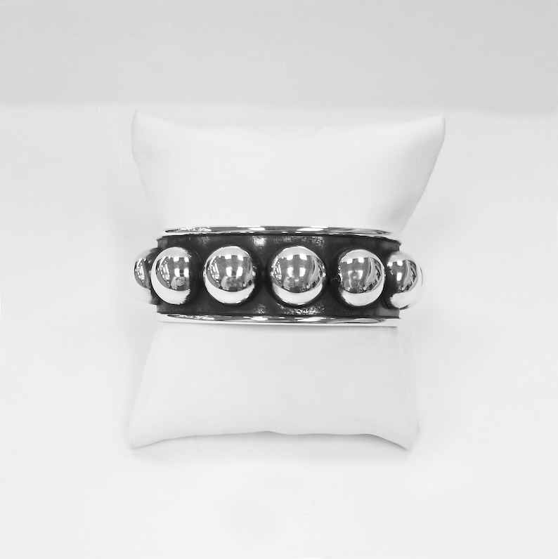 Puede incluir: Una pulsera de plata con una fila de cuentas redondas y brillantes.