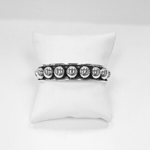 Puede incluir: Una pulsera de plata con una fila de cuentas redondas.