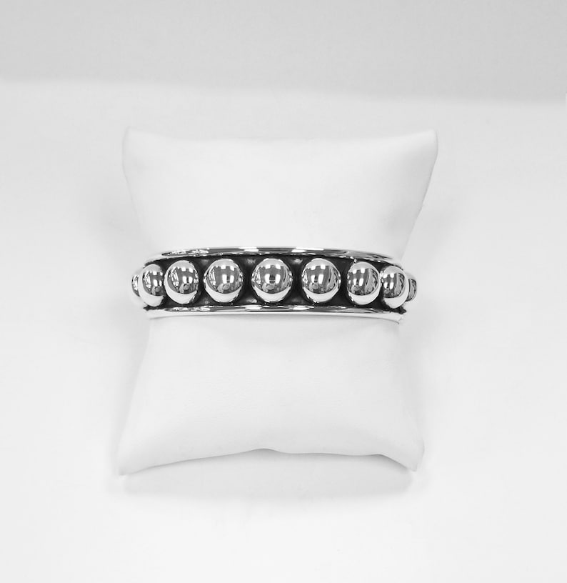 Puede incluir: Una pulsera de plata con una fila de cuentas redondas.