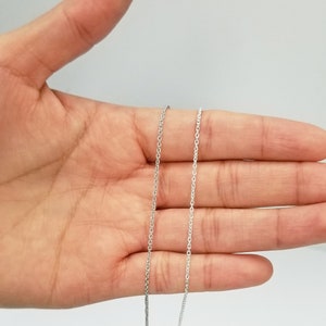 May include: Two silver chains of different lengths, laid out on a hand, showing the difference in length.