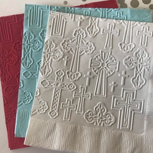 May include: Three paper napkins with an embossed pattern of crosses. The napkins are red, light blue, and white.